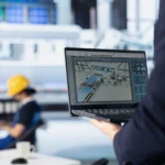 tecnico de una fabrica fotovoltaica mejora las configuraciones de los paneles solares con una computadora portatil