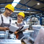 trabajadores de la fabrica analizando los resultados de produccion en una gran nave industrial