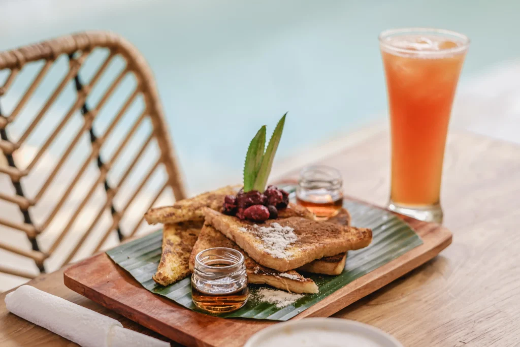 bandeja de comida y galletas en una mesa de madera junto un vaso de jugo y cafe