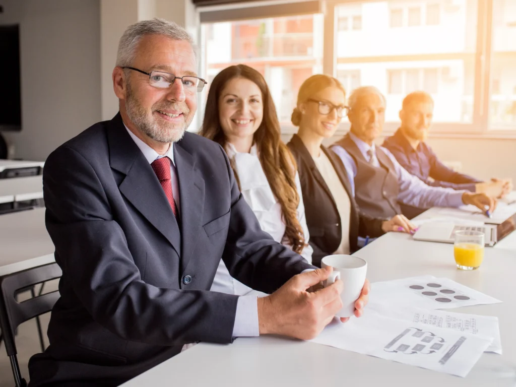 smiling senior manager with his colleagues sitting together meeting