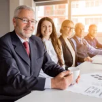 smiling senior manager with his colleagues sitting together meeting