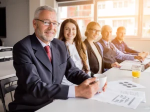 smiling senior manager with his colleagues sitting together meeting